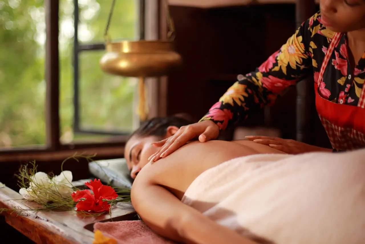 A man enjoying the Best Balinese Massage in Thane, lying on a bed while the therapist works on his shoulders to ease stress and muscle tightness.