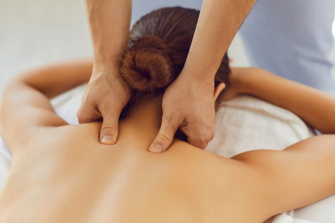 A woman enjoying the Best Deep Tissue Massage in Thane, therapist using firm pressure on her upper back to ease stress and tightness.