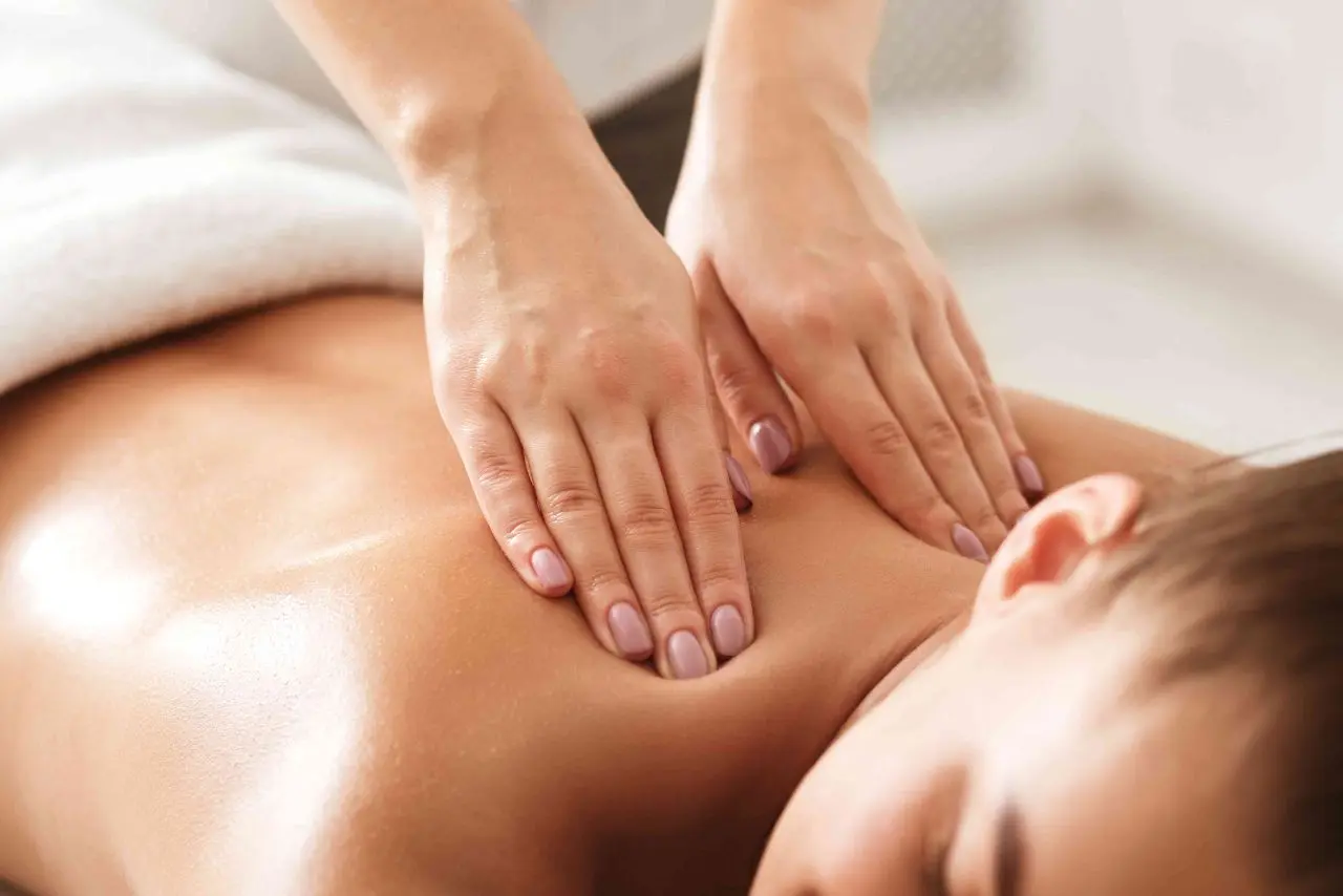 A woman enjoying the Best Swedish Massage in Thane, lying on a bed while the therapist uses smooth strokes on her back to relax and ease tension.