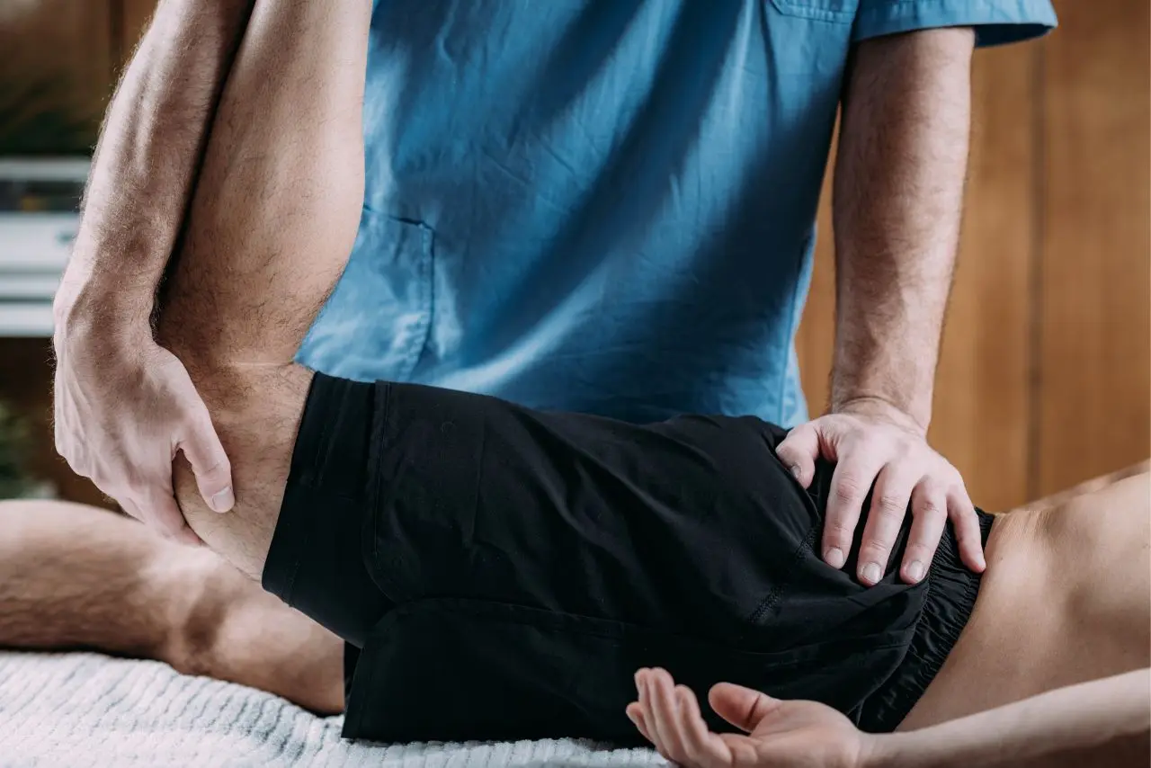 A person getting the best sports massage in Thane, therapist stretching the leg and hip area to improve joint movement and reduce body stiffness safely.